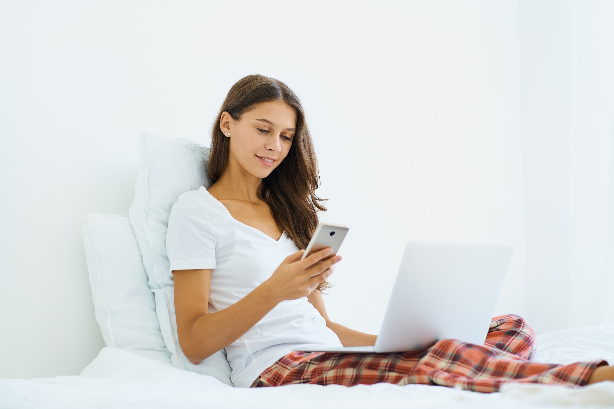Young woman shopping online, entering code from SMS message on mobile phone, online shopping